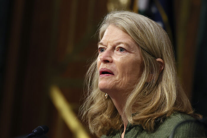 Woman speaking at Senate hearing on foreign aid and public broadcasting cuts in a formal setting