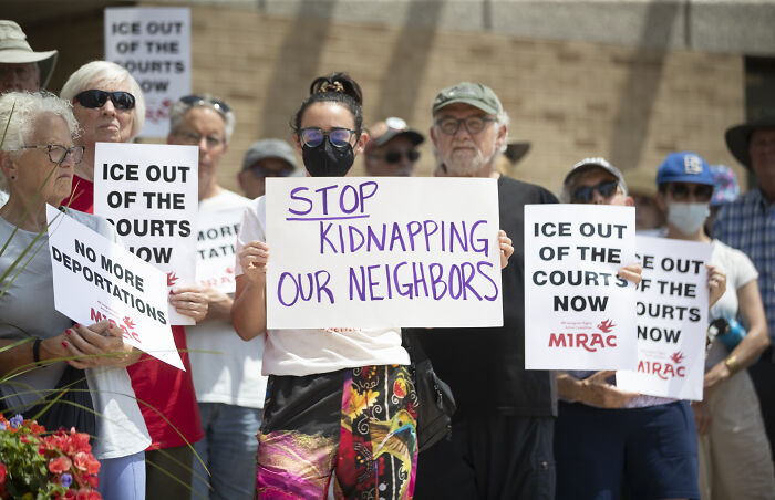Protesters holding signs against deportations and ICE, highlighting immigrant families' fear of separation and self-deportation.
