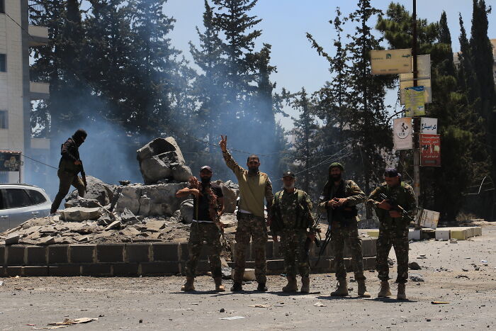 Syrian fighters stand on a rubble-strewn street during ongoing fighting after the Assad regime fell in December.