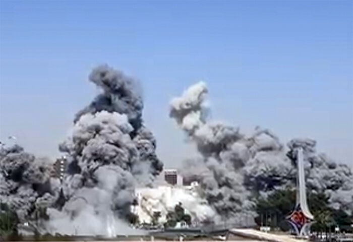 Thick clouds of smoke rising over a city in Syria amid ongoing fighting and Israel involvement in the conflict.