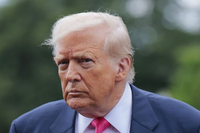 Donald Trump outdoors in a suit, with a serious expression related to his cringe dating remark on Howard Stern.