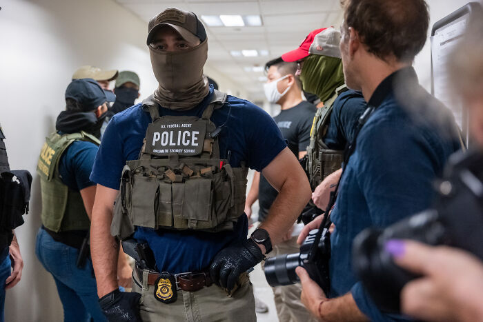 Federal immigration police officers in tactical gear conducting an operation amid fear of separation in immigrant families.