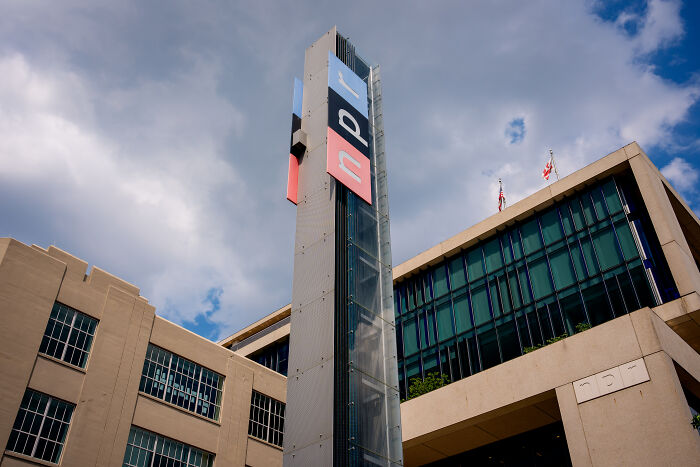 NPR building exterior with a tall logo tower under a partly cloudy sky, related to Trump&rsquo;s quest to sue and silence critics.
