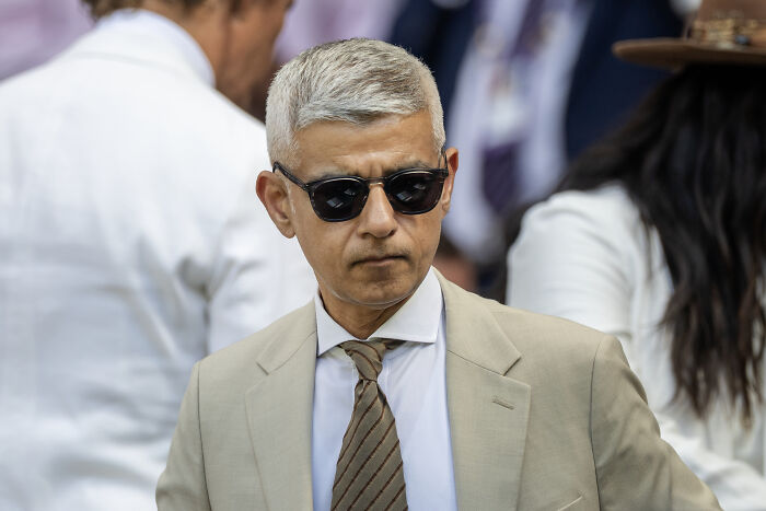 London Mayor wearing sunglasses and beige suit at a press briefing, amid political discussions involving Trump and Starmer.