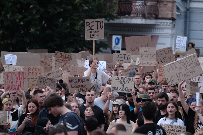Crowd protesting with signs demanding veto and opposing controversial anti-corruption law changes by Zelenskyy.
