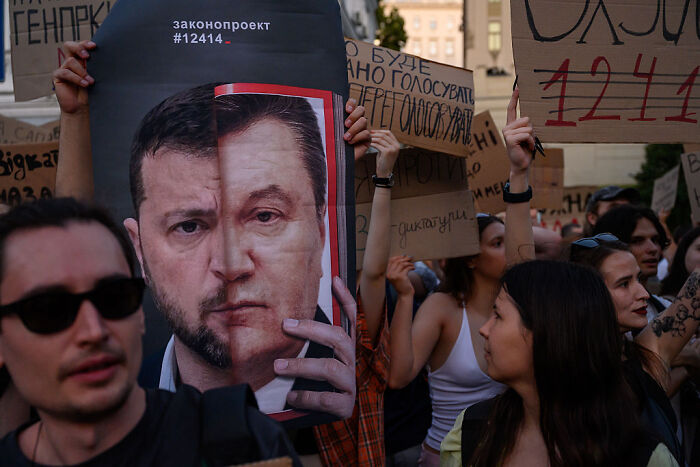 Protesters holding signs during a demonstration against changes affecting anti-corruption agencies in Ukraine.