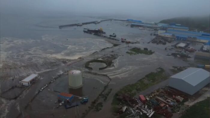 Flooded coastal area with damaged structures and vehicles after tsunami waves strike Hawaii following a powerful quake near Russia.