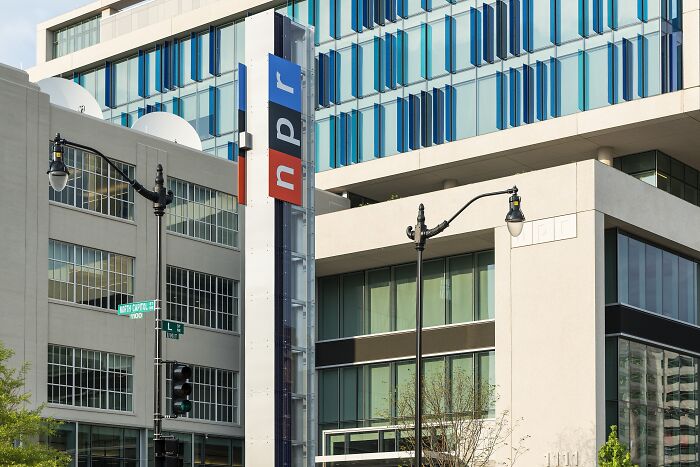 NPR headquarters building with signage in an urban setting, relating to public broadcasting and Senate budget cuts.