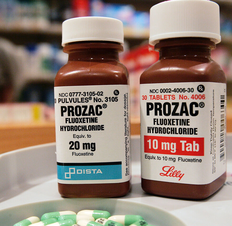 Two bottles of Prozac medication with pills in a dish, highlighting Big Pharma's role in Alzheimer's research concerns.