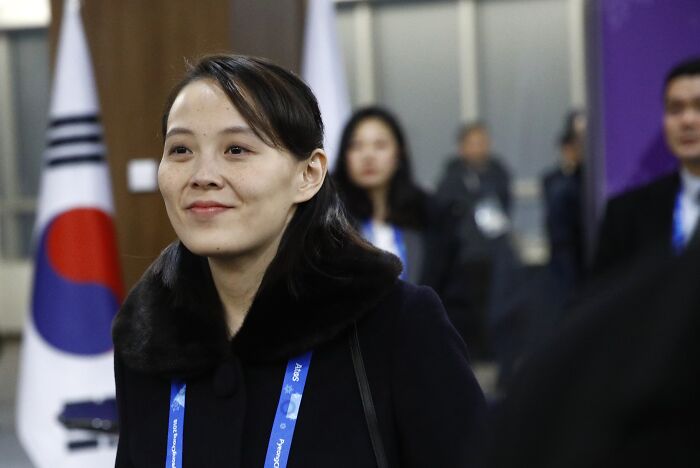 Kim Jong Un&rsquo;s sister in a black coat attending an event with the South Korean flag in the background.