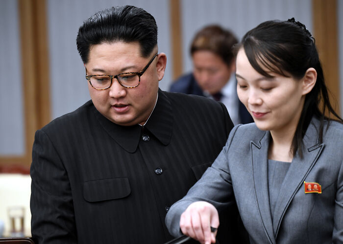 Kim Jong Un&rsquo;s sister in a grey suit with a pin, engaging with Kim Jong Un in black, rejecting South Korea dialogue efforts.