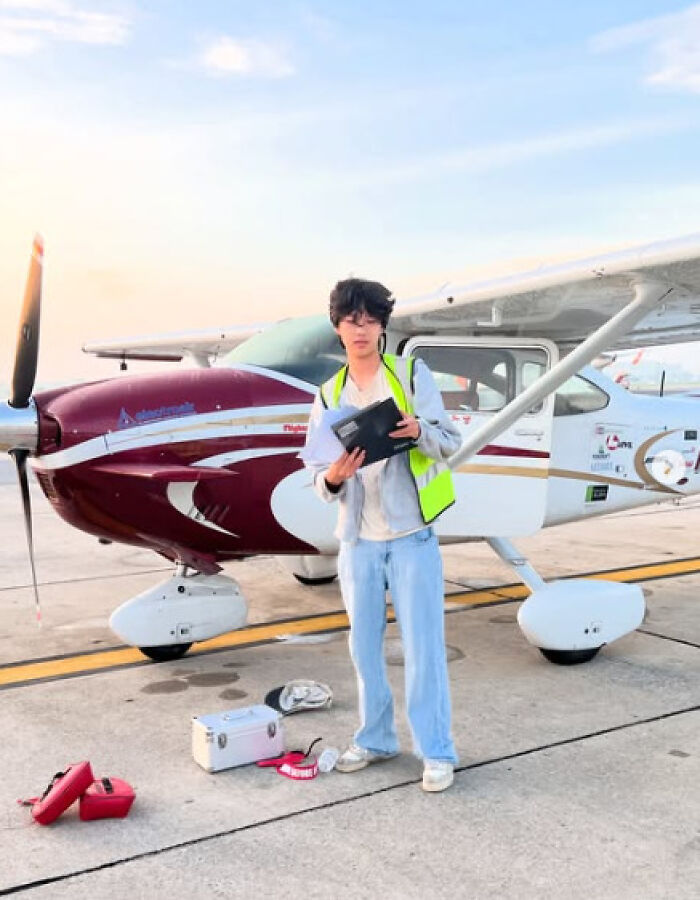 US teen pilot standing next to small airplane on runway preparing for solo flight across continents supporting cancer cause.