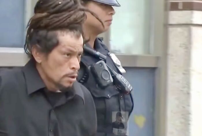 Suspect being escorted by a police officer in connection with brazen kidnapper lifting boy at Coney Island incident.