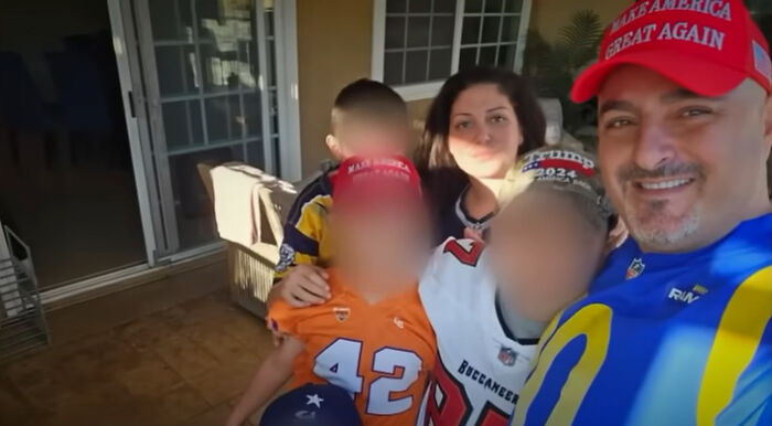 Family photo with Iranian MAGA supporter wearing red hat and blue jersey, posing outdoors with children and woman behind them.
