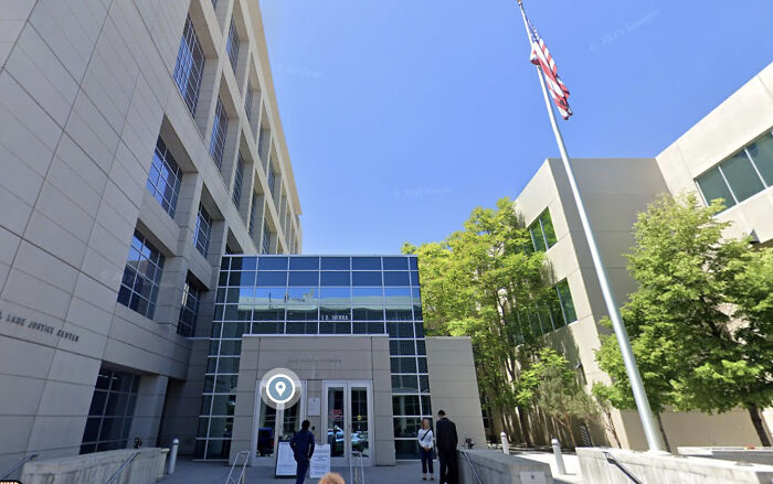 Nevada courthouse exterior with people standing outside under clear blue sky and American flag on flagpole