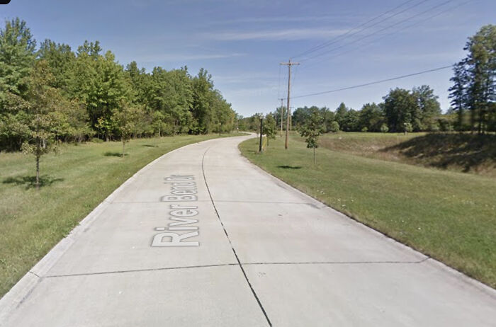 Ohio police officer killed in ambush shooting; empty street with trees and clear sky along River Bend Dr.