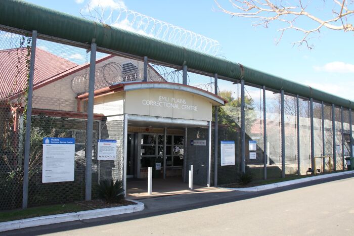 Emu Plains Correctional Centre entrance with high fencing and barbed wire under a clear sky, related to officer disturbing remark case.