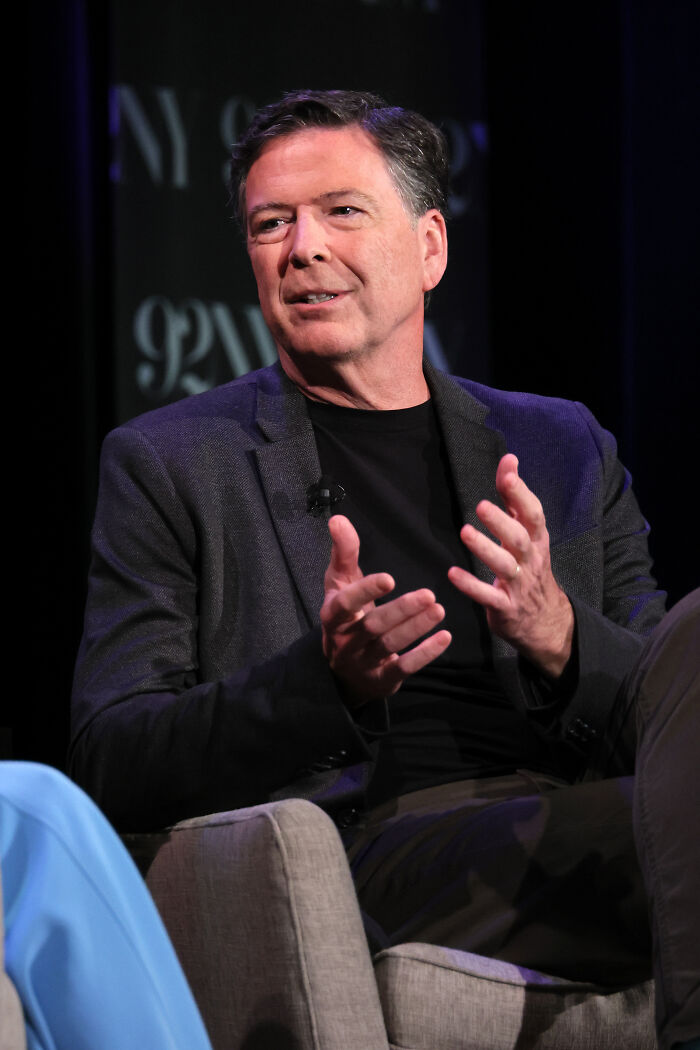 James Comey speaking at an event, wearing a dark blazer and black shirt, discussing DOJ and high-profile prosecutions.