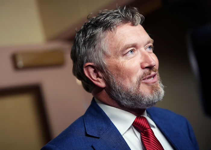 Mike Johnson in a suit and red tie, speaking about Ghislaine Maxwell and her potential impact on the U.S.