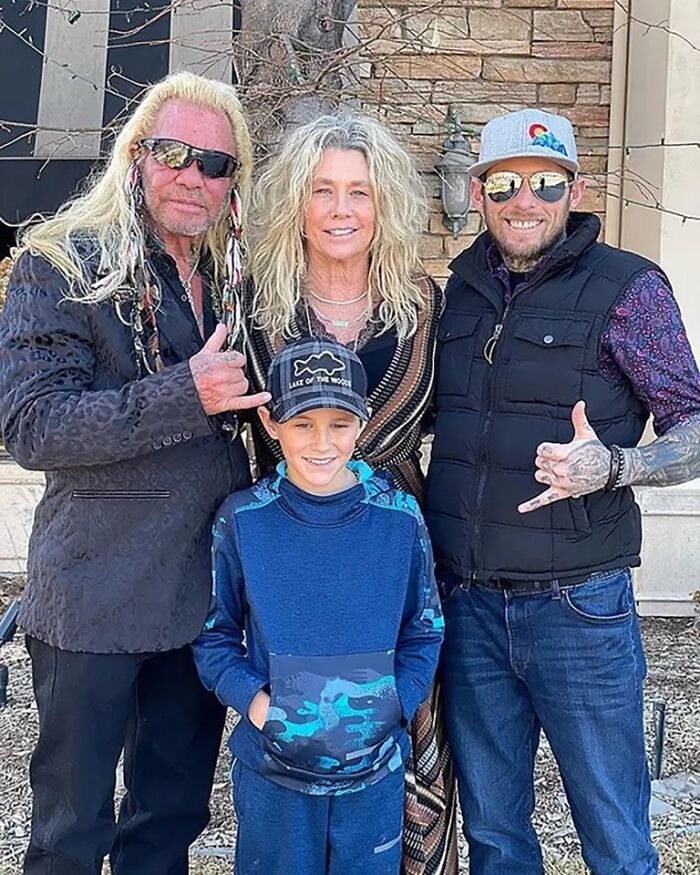 Dog The Bounty Hunter&rsquo;s family posing outside a home, featuring his step-grandson and father in casual attire.