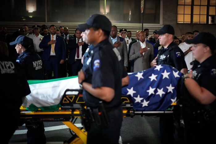 NYPD officers carrying a flag-draped stretcher as officials and civilians honor fallen NYPD officer after New York shooting incident