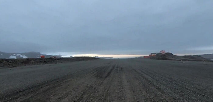 Antarctic landscape with a gravel runway and distant buildings where US teen was held during solo flight for cancer cause.
