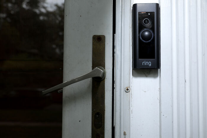 Ring video doorbell mounted next to a door handle, highlighting concerns about privacy in public spaces and surveillance technology.