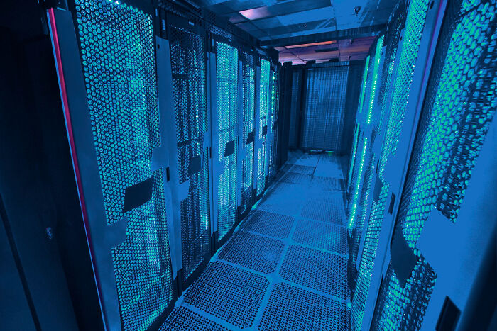 Server room with glowing blue lights, representing the complexity of LLMs discussed in experts' AI warnings.