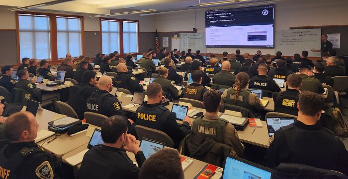 Law enforcement agencies gather in a briefing room during manhunt for Montana bar shooting suspect warning he may return.