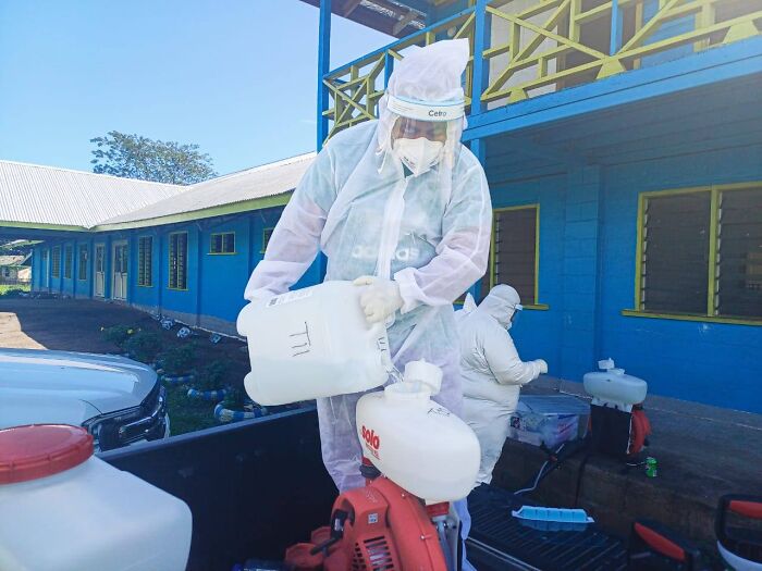 Health workers in protective gear preparing equipment for Pacific Islands dengue fever outbreak amid rising climate risks.