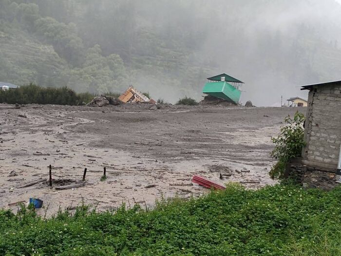 Severe flash floods sweep away town buildings, leaving debris and mud covering the landscape in a devastated area.