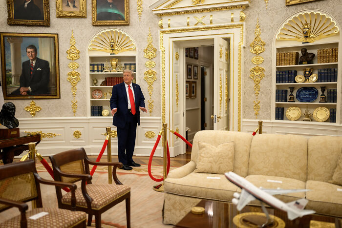 Former President Trump standing in the ornate Oval Office with golden decor and classic furniture visible around him.