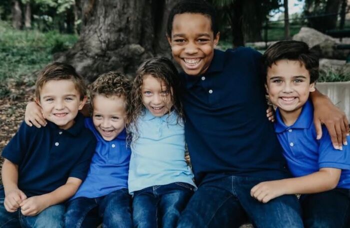 Group of smiling children sitting outdoors, illustrating family connection related to Giovanni Pelletier&rsquo;s story.