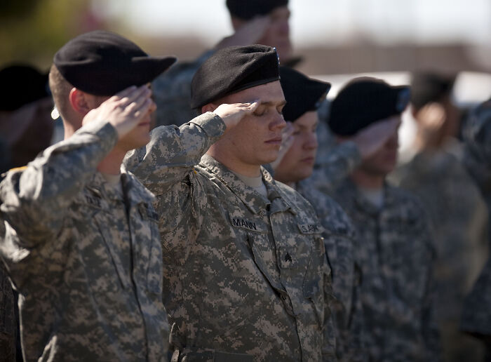 U.S. Air Force service members in uniform saluting during an official military ceremony outdoors.