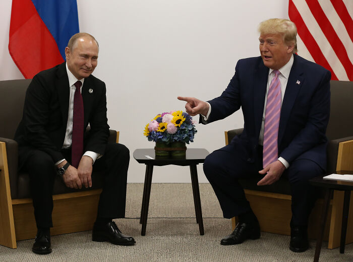 Donald Trump in a suit pointing while talking to Vladimir Putin during high-stakes meeting involving Alaska and Russia.
