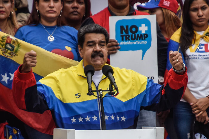 Venezuelan President Nicol&aacute;s Maduro speaking at a rally with supporters holding flags and anti-Trump signs.