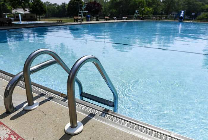 Empty swimming pool with metal ladder in focus on a sunny day symbolizing a 9-year-old girl&rsquo;s courageous move after attack