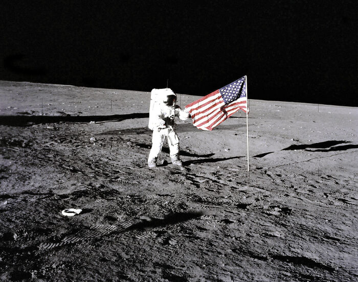 Astronaut on the moon next to the American flag, symbolizing NASA&rsquo;s plans for a fast-tracked nuclear reactor mission.