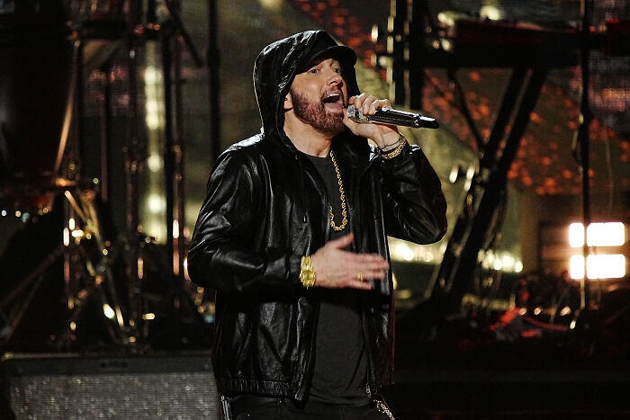 Eminem performing on stage wearing a black leather jacket and chain, highlighting early views on MAGA going viral.