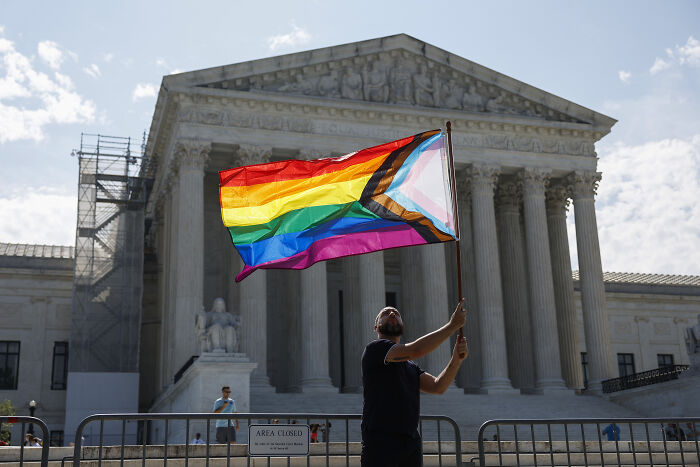 Person waving a Pride flag outside the Supreme Court amid a fresh push to dismantle same-sex marriage in a critical battle.