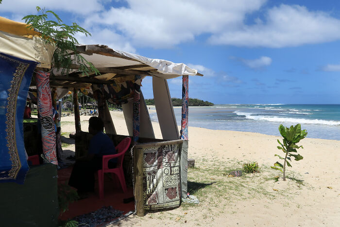 Pacific Islands beach hut with person sitting, highlighting dengue fever and climate-driven health risks in the region.
