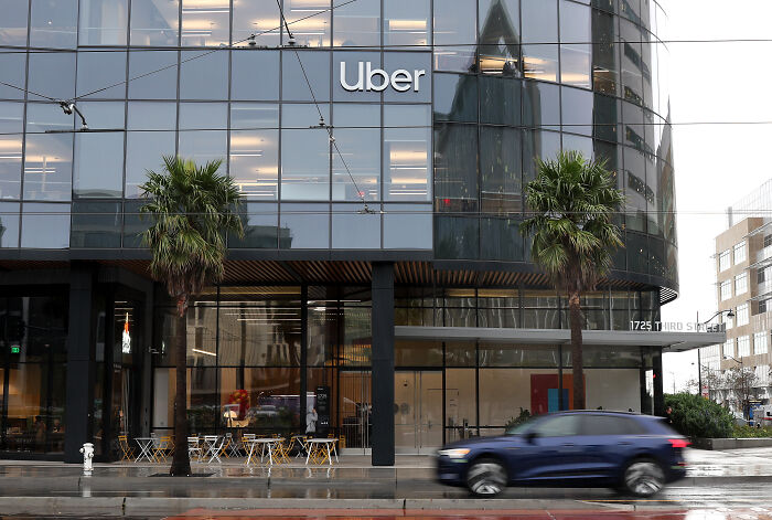 Uber office building with glass windows and palm trees, highlighting concerns over driver screening failures and related lawsuits.