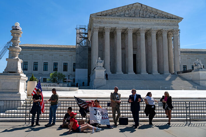 Protesters gather outside the Supreme Court building discussing Jan 6 Capitol rioter military funeral honors decision.