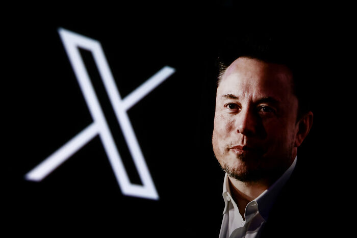 Elon Musk with a serious expression, against a dark background featuring the X logo, related to child exploitation economy.