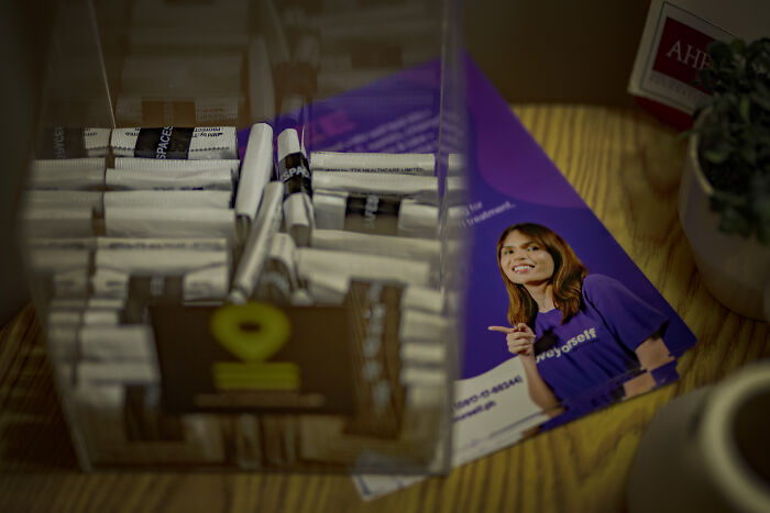 Pamphlet on women's reproductive rights next to contraceptive packets on a wooden surface illustrating health cuts impact.