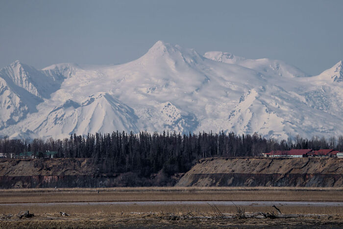 Snow-covered mountains and forest landscape in Alaska, related to Trump confusing Alaska with Russia ahead of Putin meeting.