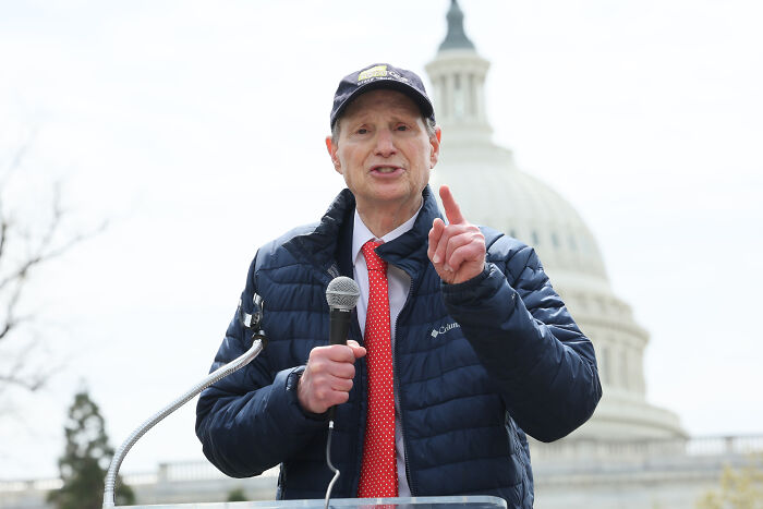 Senator speaking outdoors near Capitol, addressing the Epstein files with focus on DOJ secrets and public exposure.
