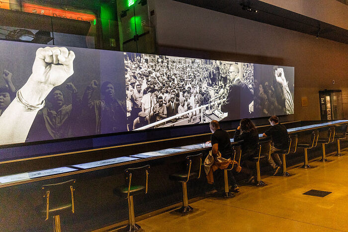 Visitors observe a Smithsonian exhibit featuring historical images related to slavery and civil rights movements.