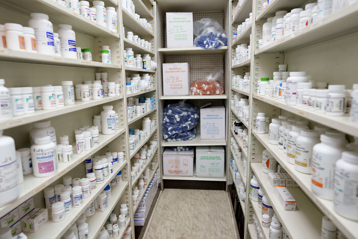 Shelves filled with various prescription drug bottles in a pharmacy, illustrating big pharma drug pricing challenges.