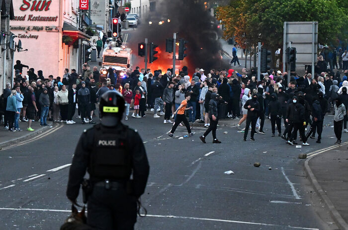 French cops in riot gear face a large crowd amid clashes with dad and son trying to board UK-bound boat.
